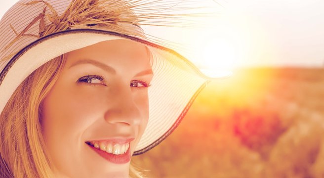 Beautiful young woman posing in the field with sunset in background. Filter used on photo