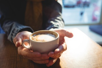 Close-up of woman holding coffee cup at cafeteria