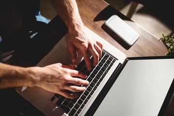 High angle view of customer typing on laptop keyboard at cafe