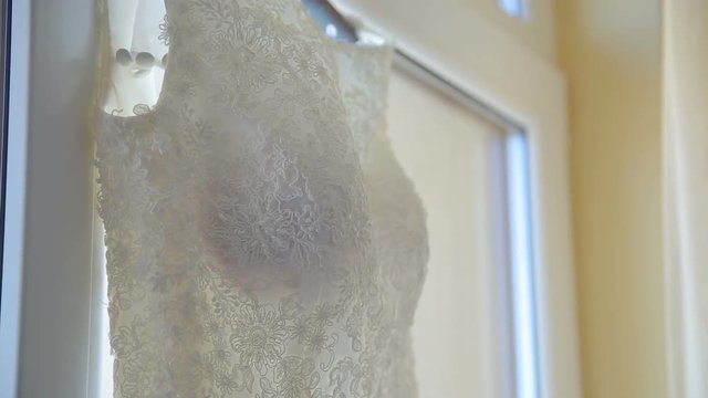 Close up of wedding dress hanging on a window