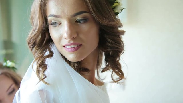 Bride's friends help to wear wedding dress, when she hold the parfume