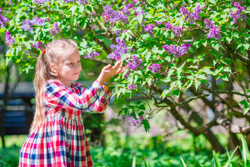 Little adorable girl smelling colorful flowers outdoors