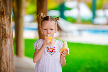 Adorable little girl having breakfast at outdoor cafe