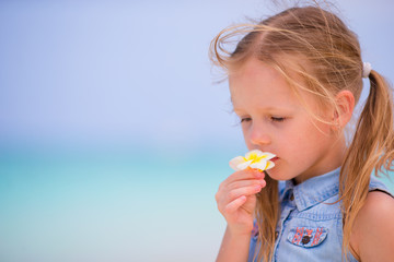 Portrait of adorable little girl with flower on beach summer vacation