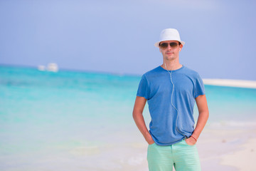 Young man on beach vacation. Happy boy enjoy beach and warm weather while walking along the ocean