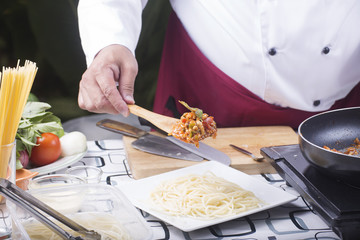 Obraz na płótnie Canvas Chef putting chicken sauce to spaghetti on the plate