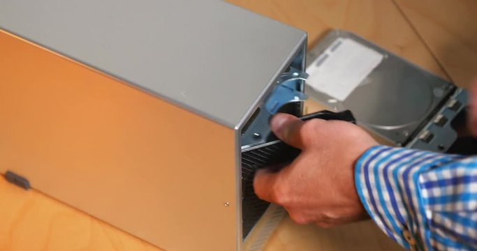 An IT technician removes five hard drives from an external RAID array.  	