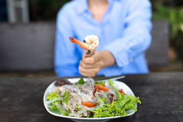 Hand holding fork with prawn and glass noodle salad