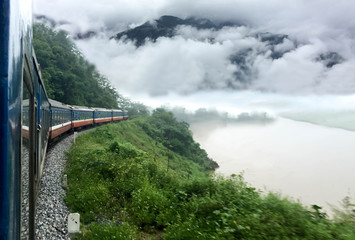 Obraz premium Train passing a beautiful fog mountains and river
