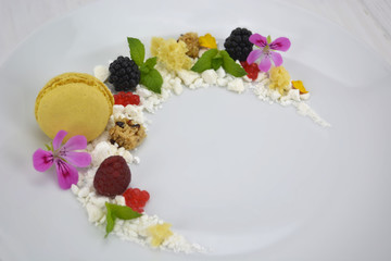 Presentation dessert, biscuit, fake caviar, molecular spheres, macarons, maltodextrin, chocolate, and edible flowers.