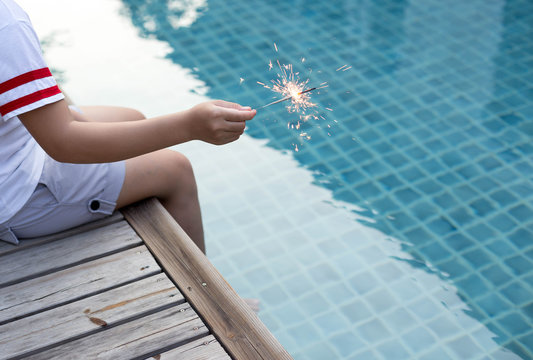 Teen girl playing sparkler by swimming pool