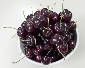 Red cherries in white bowl, selective focus, with bright light