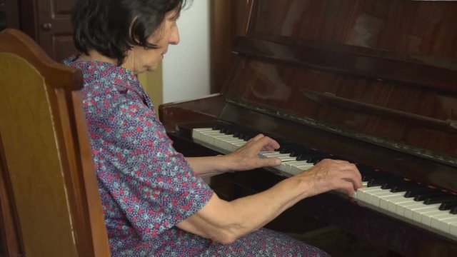 Old happy grandmother is playing the piano
