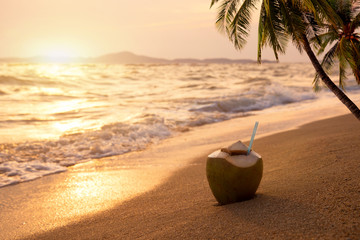 Fresh coconut cocktails on sandy tropical beach at sunset time - vacation in summer. vintage color...