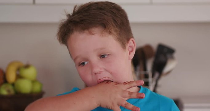 4K Young boy licking chocolate cake mixture off his fingers