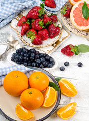 Fresh fruits and berries on a white wooden board.
