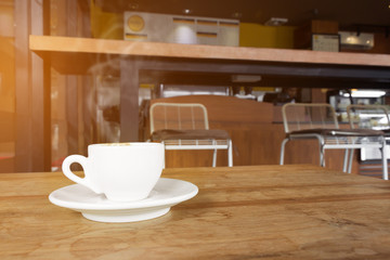 cup of coffee with smoke on wooden table in cafe.