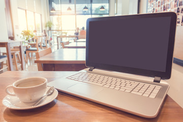 coffee with laptop on wooden table in cafe.