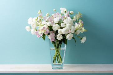 青い背景と白い薔薇とピンクのデンファレと花瓶