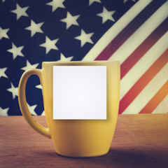 Yellow coffee cup on wooden table with USA flag background with