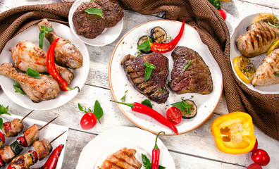 Assorted grilled meats and vegetables on a wooden table.