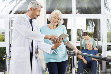 Doctor Showing Reports On Computer To Woman In Fitness Center