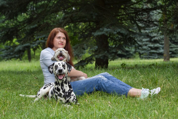 Dogs and their owner sitting on the grass (dalmatian in focus)