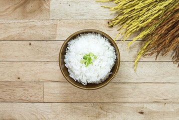 Cooked rice and paddy rice on wood table at top view