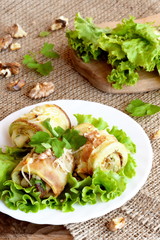 Fried zucchini stuffed with cheese, walnuts and herbs. Homemade zucchini appetizer arranged on lettuce and a plate. Fresh green lettuce on a wooden board. Healthy and delicious summer food