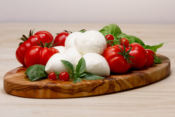 Mozzarella, heirloom tomatoes, basil leaves on a wooden serving