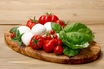 Mozzarella, heirloom tomatoes, basil leaves on a wooden serving