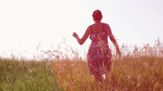 Slow motion video - woman running on the field away from camera. Full HD people stock footage.  
