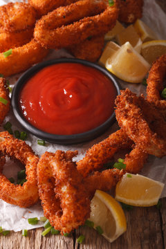 crispy fried squid rings with ketchup and lemon close-up. vertical
