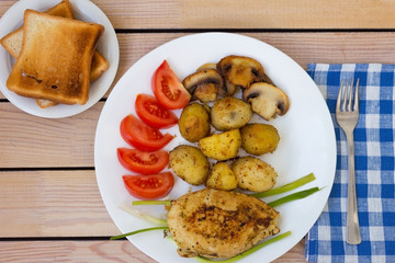 fried chicken fillet with potatoes tomatoes and mushrooms