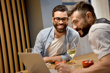 Trendy guys in bar connected with laptop