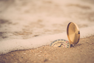 Compass on sand beach and sea wave