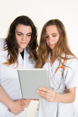 Two women doctors looking at tablet isolated on white