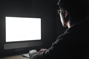 Back view of man in glasses using blank screen computer