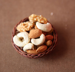 Mix of dry nuts and fruits close-up with wooden basket