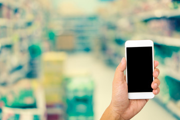 Hand hold smartphone on blur business shopping mall background
