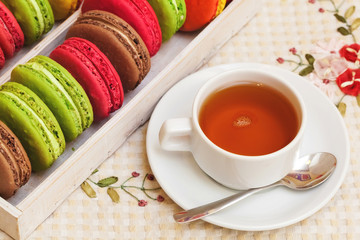 Traditional french colorful macarons in a box, cup of tea