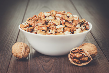 walnuts in the white bowl on brown wooden table