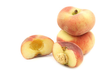 Fototapeta na wymiar fresh colorful flat peaches (donut peaches) and a cut one on a white background