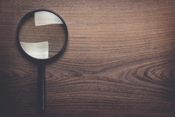 magnifying glass on the dark brown wooden background