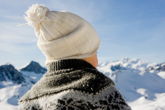 Baby boy wearing knitted bobble hat, mountain scenery in background