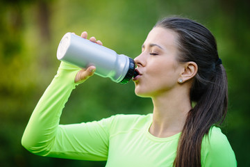 Portrait of young beautiful brunette woman drinking water, outdoor