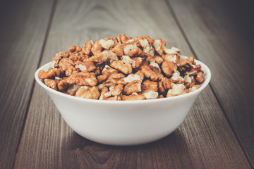 walnuts in the white bowl on brown wooden table