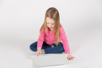 Kleines Mädchen / Heranwachsende sitzt frontal vor Laptop