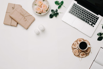 Workspace with laptop, coffee, roses in tray on white background