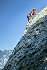 young boy is climbing to the top of a mountain